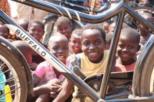 Pictures of some chiildren in Chilaweni, Malawi. They are looking through the frame of a bicycle ambulance.
